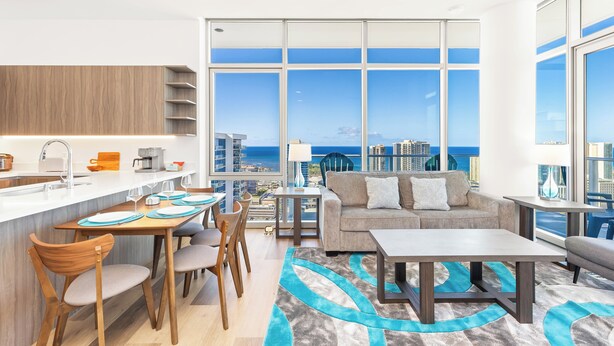 Una sala de estar moderna con vista a la ciudad, una cocina con cubierta blanca y un comedor con sillas de madera.