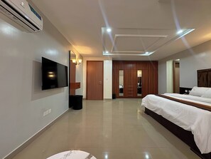 A modern hotel room with a flat-screen TV, a bed, a wardrobe, and a bathroom.