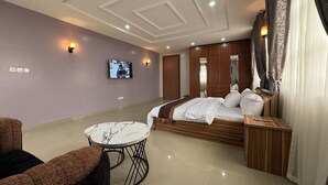 Une chambre d’hôtel avec un lit, une télévision, une petite table et un canapé.