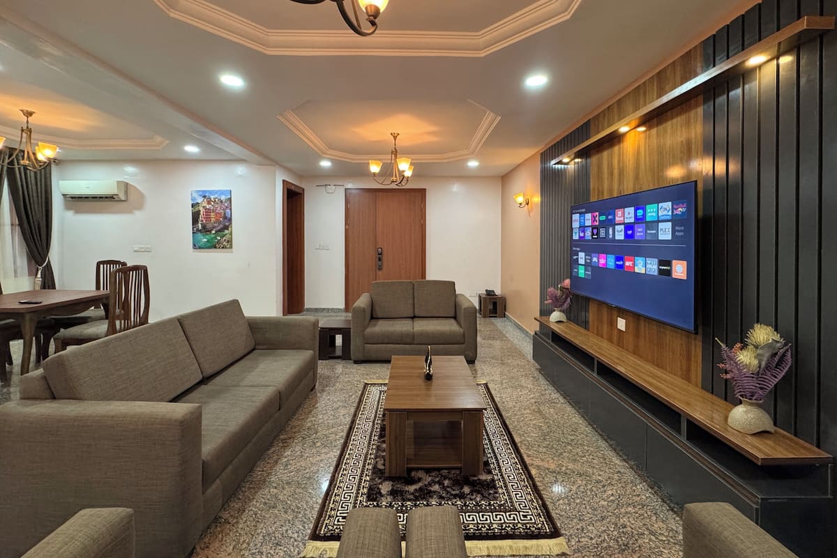 A modern living room with a sofa, coffee table, and TV wall-mounted.