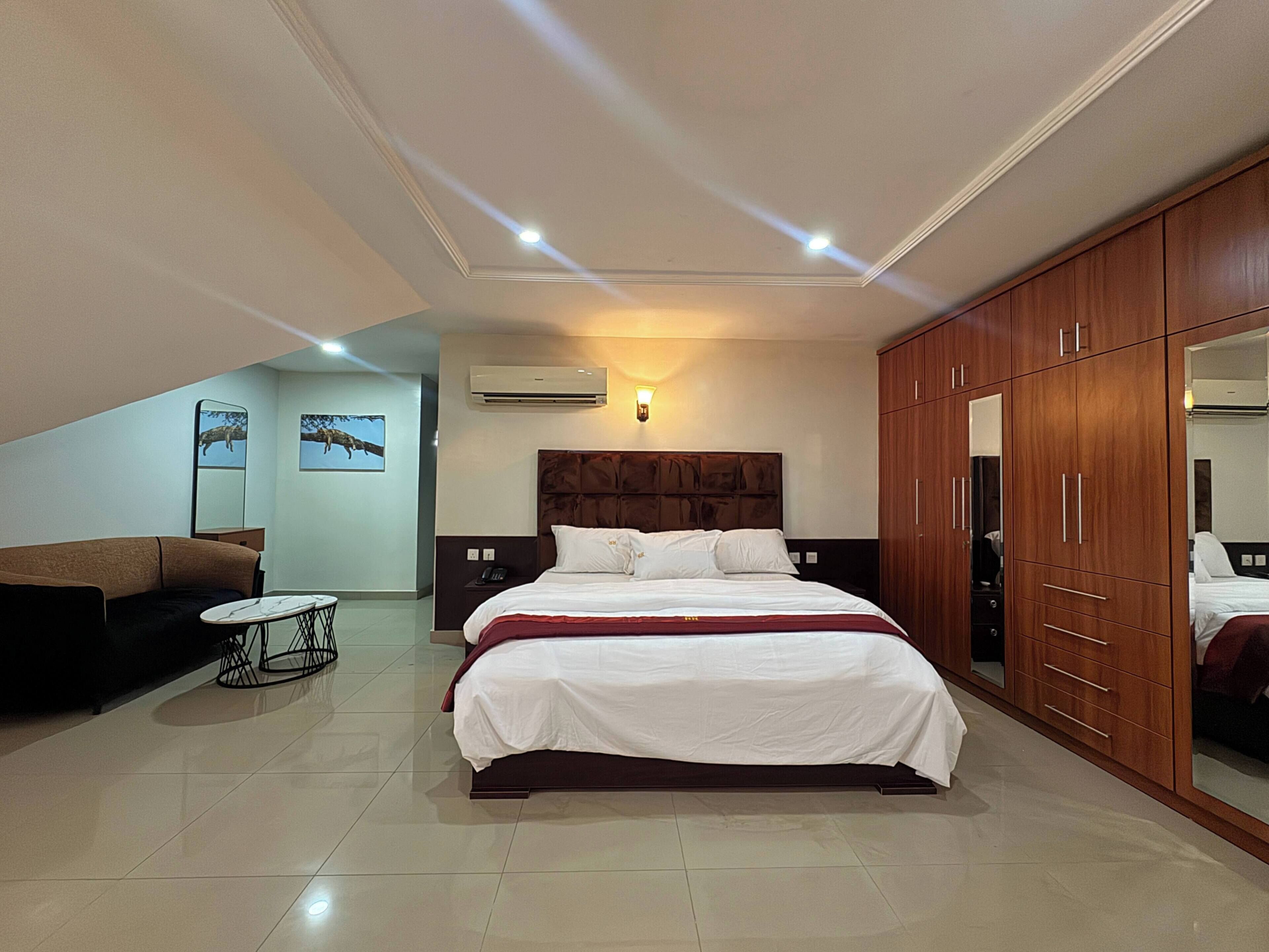 A bedroom with a bed, a wardrobe, a sofa, and a small table.