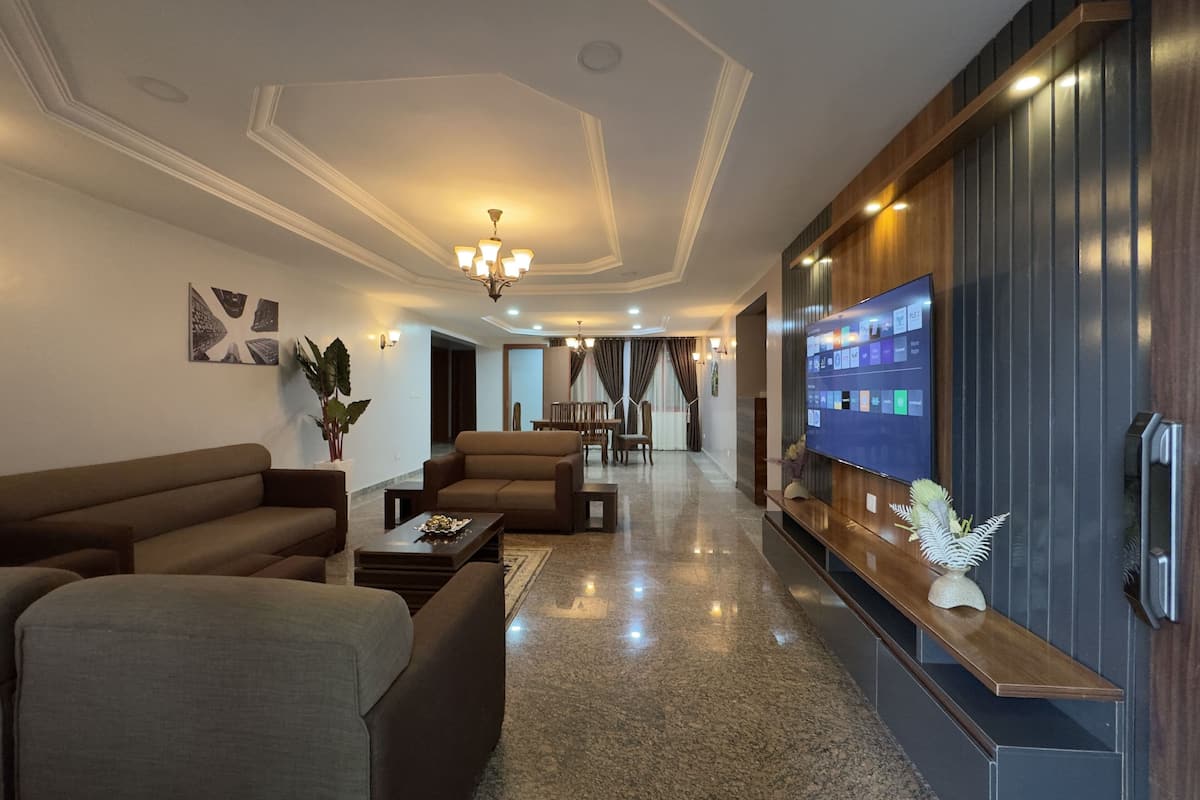 A modern hotel lobby with a seating area, a flat-screen TV, and a reception desk.