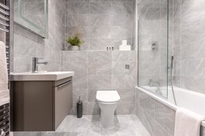 Een moderne badkamer met douche, toilet en wastafel.
