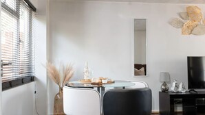 A modern living room with a round glass table, two chairs, a TV, and a decorative mirror. - Leaside House - Good access links across Southampton & New Forest (Southampton)
