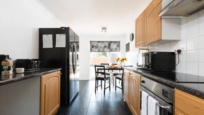 A modern kitchen with a refrigerator, microwave, and stove. There is a dining table with chairs and a window with a view. - Leaside House - Good access links across Southampton & New Forest (Southampton)