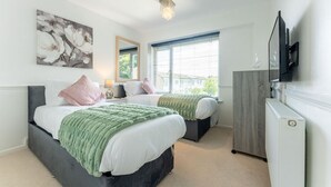 A bedroom with two beds, a mirror, a TV, and a window with blinds. - Leaside House - Good access links across Southampton & New Forest (Southampton)