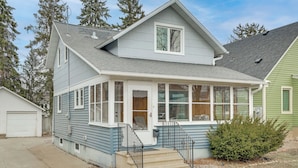 A two-story house with a covered porch, a front door, and a small front yard.