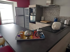 Una cucina moderna con un frigorifero in acciaio inossidabile, un forno a microonde, un tostapane e una macchina da caffè sul piano di lavoro.