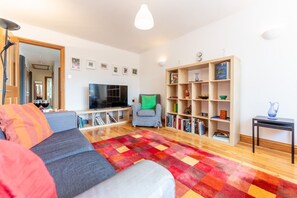 Un salon avec un canapé, un téléviseur, une bibliothèque et un miroir.