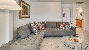 A living room with a grey sectional sofa, a glass coffee table, and a painting on the wall. - Shop & Dine! Getaway 3 Mi to Old Town Scottsdale (Scottsdale)