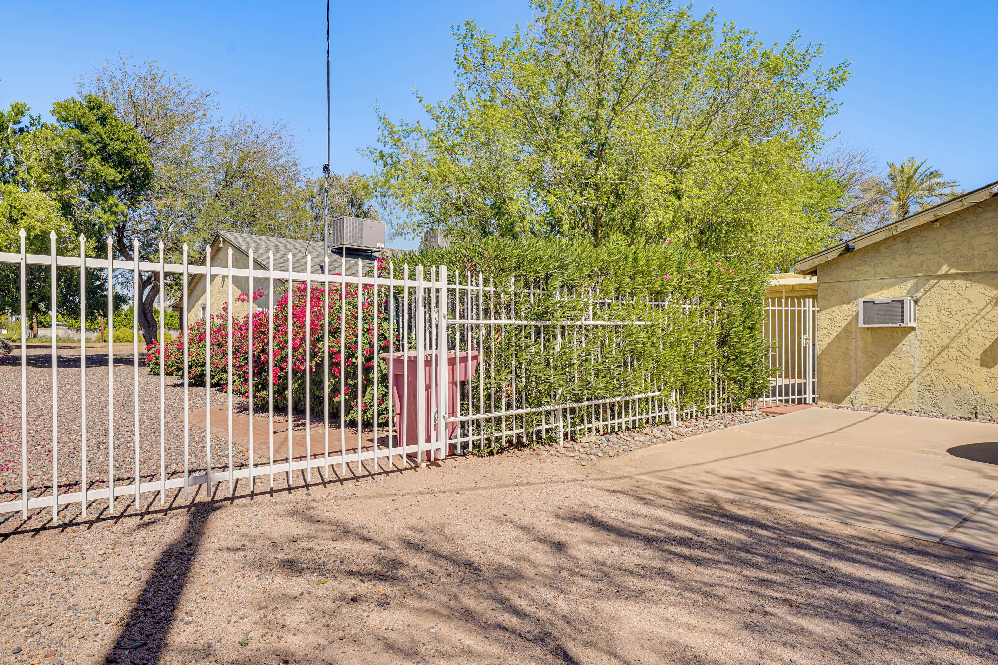 A fenced property with a building, a gravel driveway, and a tree.