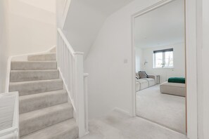 Eine Treppe führt zu einem Wohnbereich mit einer Couch und einem Fenster.