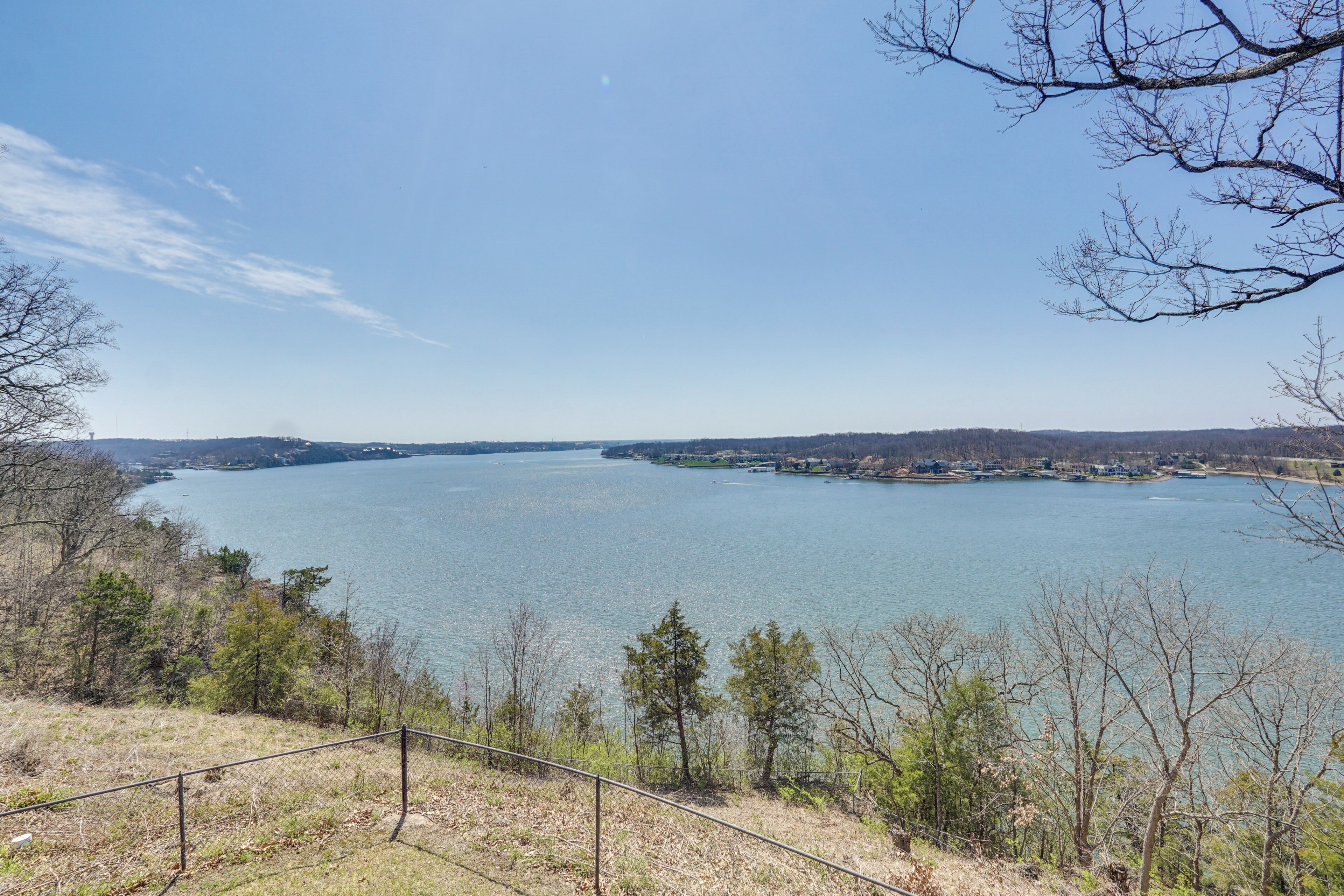 A lake with a clear view of the surrounding landscape, including trees and distant buildings.