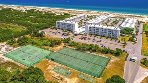 Une vue aérienne d’un hôtel composé de plusieurs bâtiments, d’un parking et d’un court de tennis.