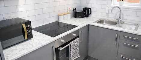 Una cocina moderna con gabinetes grises, un tostador negro, un lavamanos y una ventana con una planta.