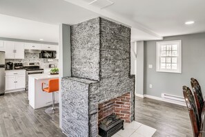 A modern kitchen with white cabinets, a built-in oven, and a stone fireplace. - Indoor Hot Tub & Sauna! Spacious Catskills Home (Cairo)