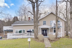 A two-story house with a front porch, a garage, and a small deck. - Indoor Hot Tub & Sauna! Spacious Catskills Home (Cairo)