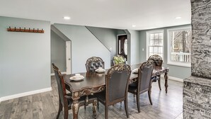 Une salle à manger avec une grande table, des chaises décorées et un escalier menant à un autre niveau.
