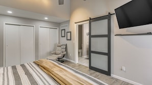 A bedroom with a bed, a chair, a sliding door, a ceiling fan, and a mounted TV. - Renovated Townhome w/ Garage, 12 Mi to St Louis (Belleville)