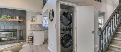 A modern kitchen with a brick wall, a built-in oven, and a dining area with a bar stool.
