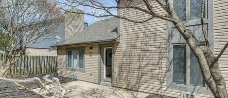 A two-story house with a front porch, a wooden fence, and a tree in the yard.