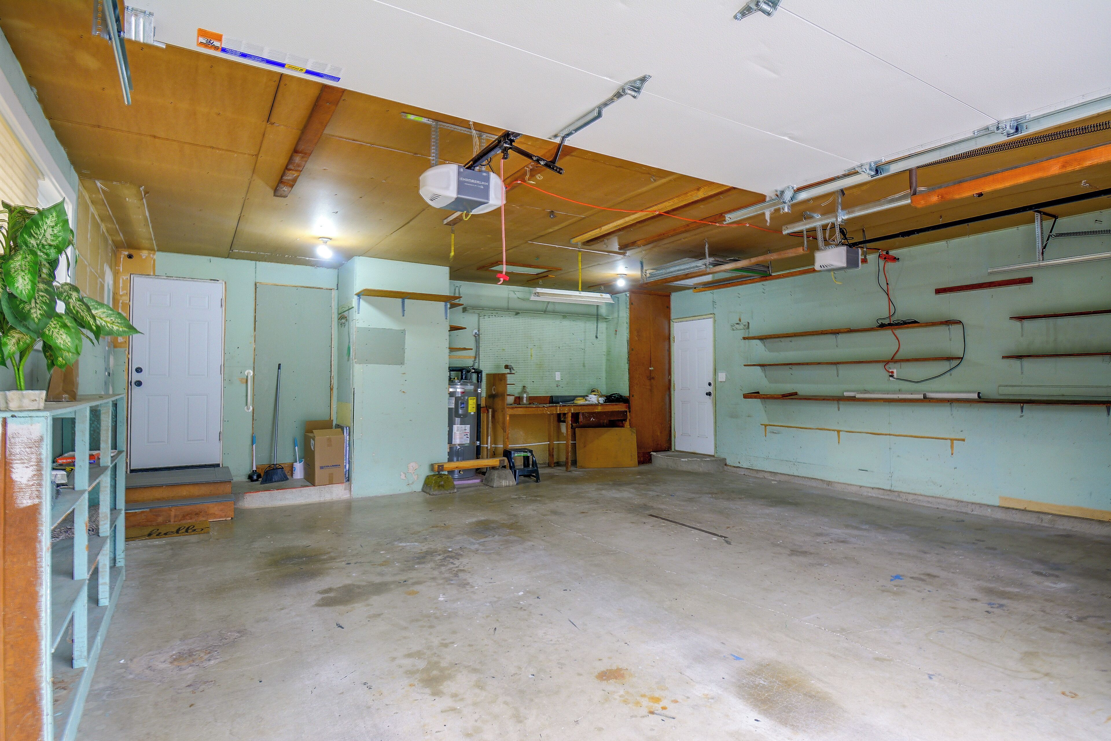 A room with a concrete floor, wooden beams on the ceiling, a ceiling fan, and a projector mounted on the wall.