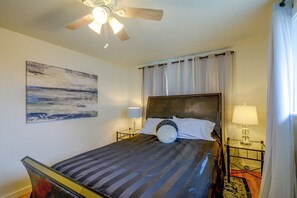 A bedroom with a bed, a ceiling fan, a painting, and a nightstand with a lamp. - 3 Mi to Point Defiance Park: Family Home w/ Yard! (Tacoma)