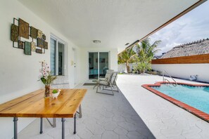 A poolside area with a wooden table, chairs, and a small potted plant. - Pool Access! Snowbird Gem in Country Club of Miami (Miami Gardens)