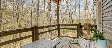 A wooden deck with a table and chairs, a rocking chair, and a potted plant.