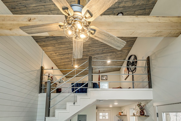 Un intérieur à plusieurs niveaux, avec un plafond en bois, un escalier et un ventilateur.