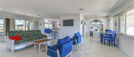 A spacious living area with a sofa, chairs, a coffee table, and a dining set.