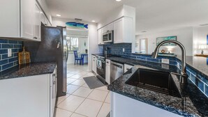 A modern kitchen with white cabinets, granite countertops, a stainless steel refrigerator, and a built-in microwave. - 2 Mi to Englewood Beach! Home w/ Private Dock (Englewood)