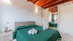 A bedroom with a bed, a nightstand, a lamp, and a wardrobe. - Casa Ale Villasimius: Cozy Two-Level Home for 4 Guests Near Beaches and Services (Villasimius)