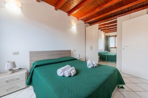 A bedroom with a bed, a nightstand, a lamp, and a wardrobe. - Casa Ale Villasimius: Cozy Two-Level Home for 4 Guests Near Beaches and Services (Villasimius)
