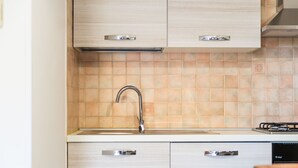 A kitchen with a modern design, featuring light-colored cabinets, a stainless steel faucet, and a tiled backsplash. - Casa Ale Villasimius: Cozy Two-Level Home for 4 Guests Near Beaches and Services (Villasimius)