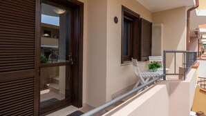 A balcony with a railing, a door, and a window with shutters. - Casa Ale Villasimius: Cozy Two-Level Home for 4 Guests Near Beaches and Services (Villasimius)