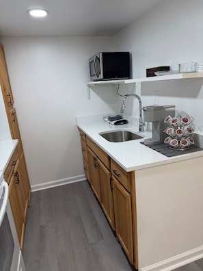 Una cocina compacta con microondas, lavabo y cafetera.