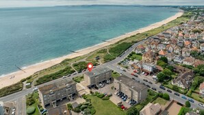 Eine Vogelperspektive einer Küstenstadt mit Strand, Wohnhäusern und einem markanten roten Marker.