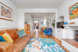 A living room with a brown leather sofa, a blue armchair, and a patterned rug.