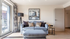 A modern living room with a sofa, a floor lamp, and a painting on the wall. - Harbour View -  Sea Views & Balcony close to Poole Town (Poole)
