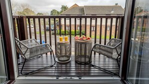 A balcony with two wicker chairs, a small table, and a glass of orange juice. - The Catalina Breeze - By the harbour, park and town with parking (Dorset)