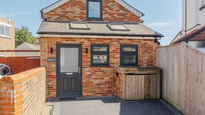 A small brick house with a black door, a window, and a wooden fence. - Tower Hide - 1 bed with parking (Boscombe)