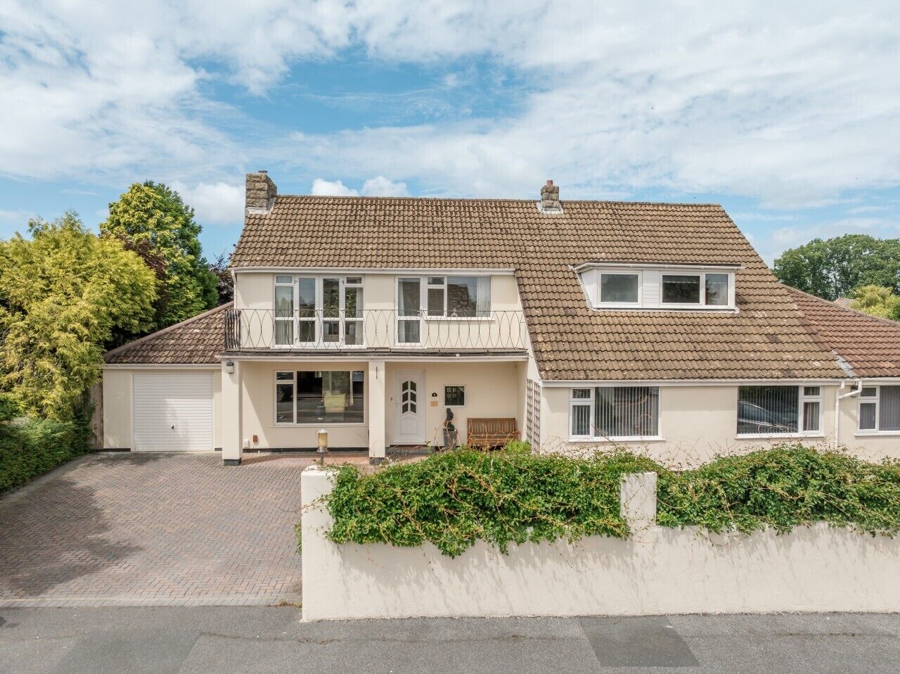 A two-story house with a tiled roof, a front porch, and a garage.