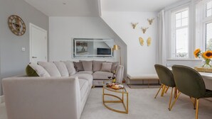 A modern living room with a sectional sofa, a coffee table, and a dining area with chairs. - Park Views - Great for places to eat and getting to the beach (Poole)