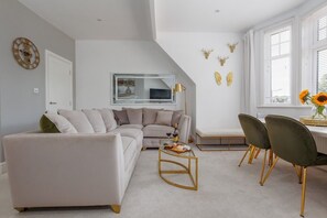 A modern living room with a sectional sofa, a coffee table, and a dining area with chairs.