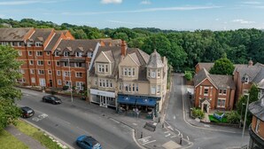 A street view with a row of terraced houses, a shop named 'Nicholas James,' and a 'SLOW' road marking. - Park Views - Great for places to eat and getting to the beach (Poole)