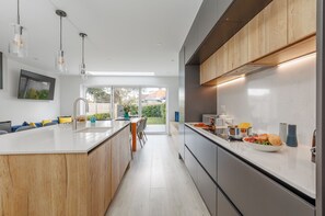 A modern kitchen with a central island, stainless steel appliances, and a view to the outdoors. - The Laurels - Family space close to a choice of beaches (Poole)