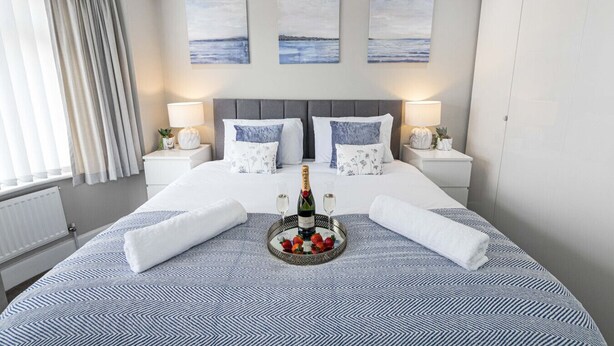 Une chambre d’hôtel avec un grand lit, deux tables de chevet, une tête de lit et trois tableaux accrochés au mur.