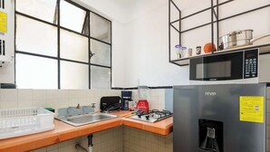Eine Küche mit Mikrowelle, Herd, Spüle und einem Fenster mit Jalousien.