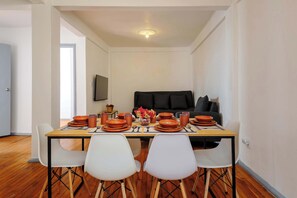 A dining area with a table set for four, a sofa in the background, and a door leading to another room. - Edificio Aurora | A Historic Downtown Apartment (Centro)